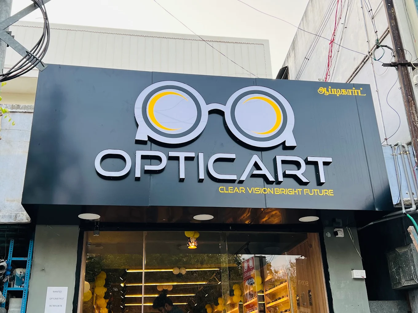 The Opticart Musiri storefront: a charcoal signboard with the gold spectacle logo and the words Clear Vision Bright Future
